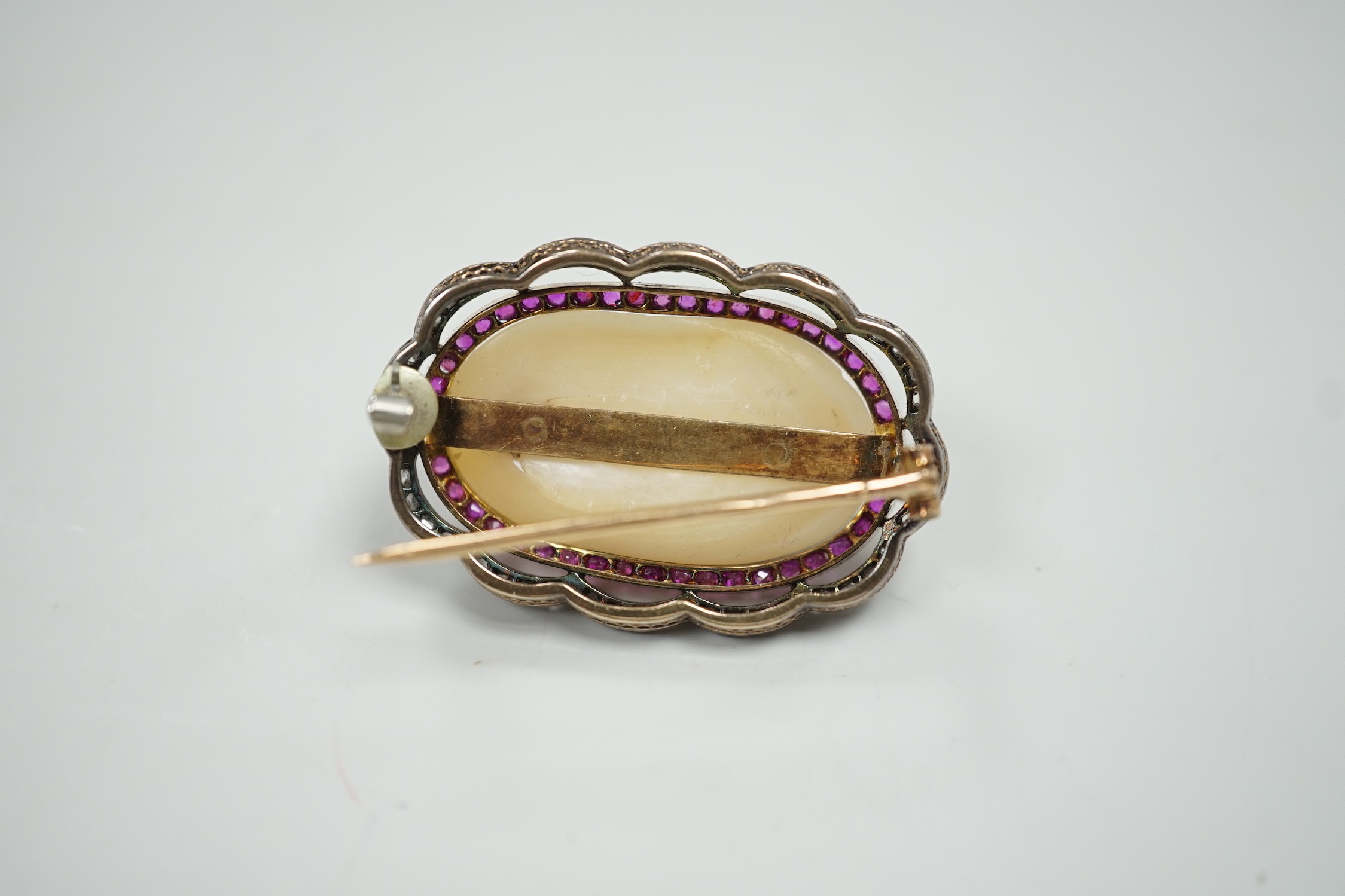 An early 20th century French yellow metal (18ct poincon mark on pin), white metal and mabe pearl set oval brooch, bordered by concentric rows of rubies and rose cut diamonds, 38mm, gross weight 17.3 grams.